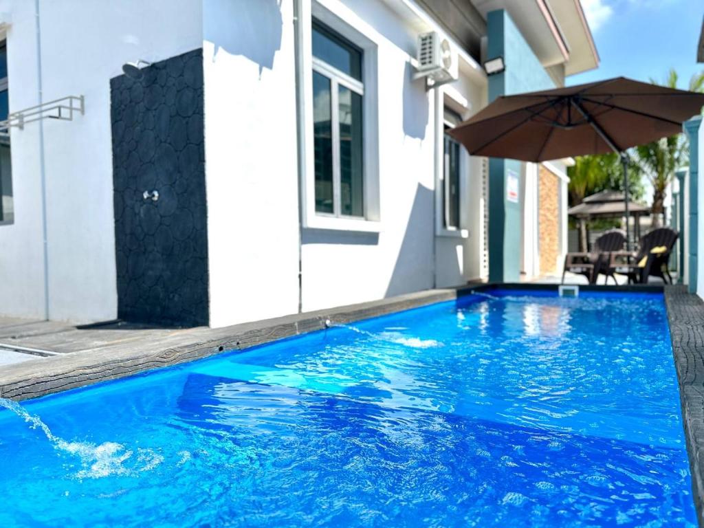 马六甲Bandar Melaka Family Bungalow Private Pool BBQ WiFi Netflix的一座房子旁带遮阳伞的游泳池