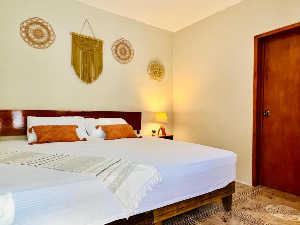 奇琴伊察CASA VICTORIA的卧室配有一张带白色床单和橙色枕头的大床。