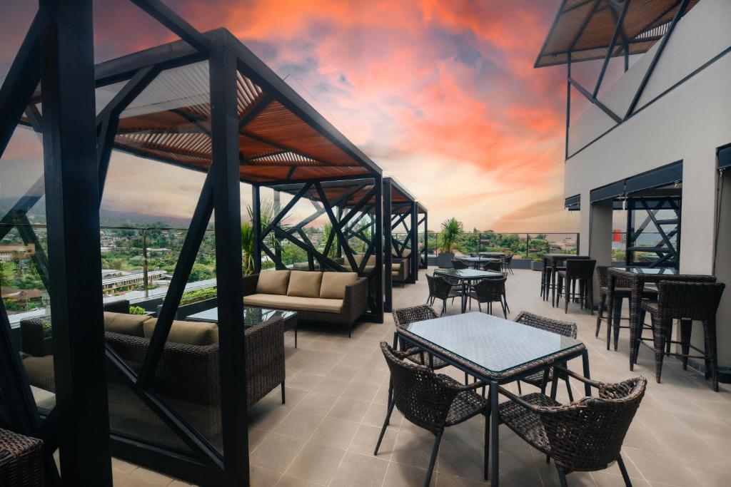 PinelengRogers Hotel Manado的一个带桌椅的屋顶露台,享有日落美景