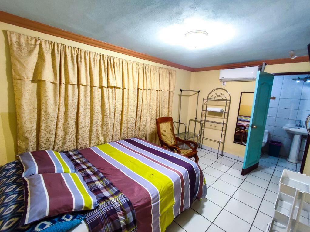 马那瓜Hotel Fuente de Paz Managua的一间卧室配有一张床、一把椅子和镜子
