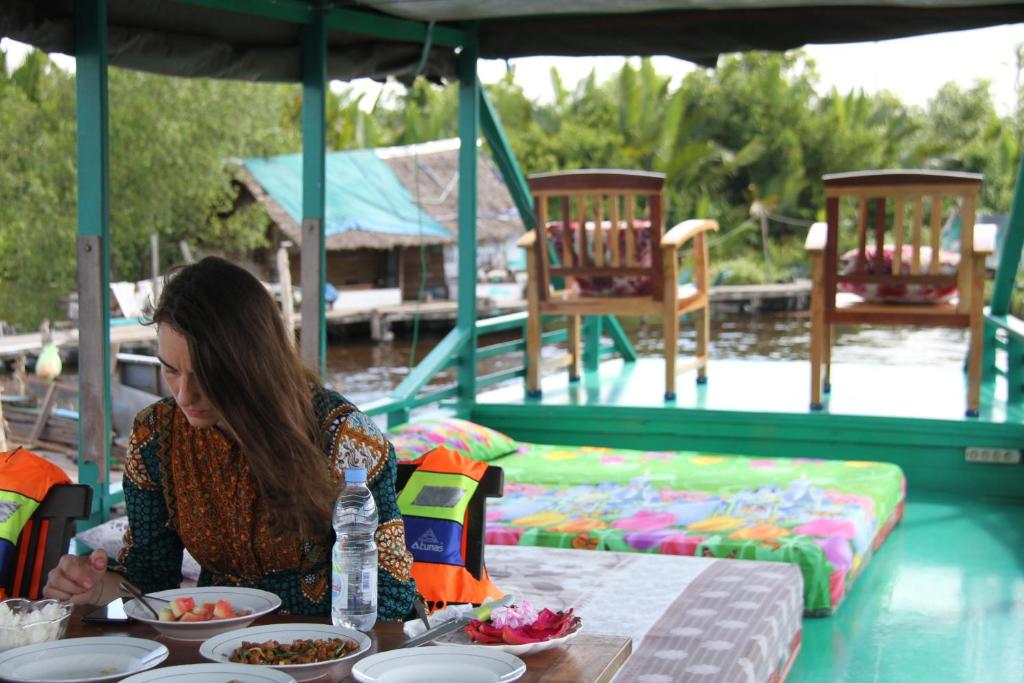 庞卡兰布翁Orangutan Kelotok Houseboat for 6 person的坐在餐桌上吃盘子的女人