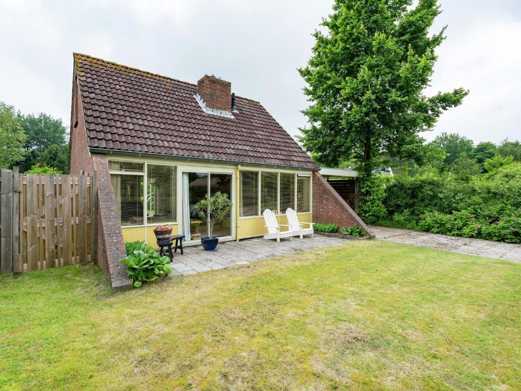 劳雷尔苏格Cosy holiday home in Lauwersoog的一座小房子,设有2把白色椅子的庭院