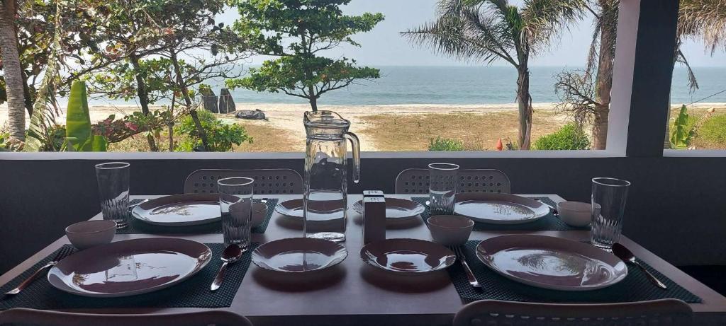 阿勒皮Happy Seas Beach Villa的一张带盘子和玻璃的桌子,享有海滩美景