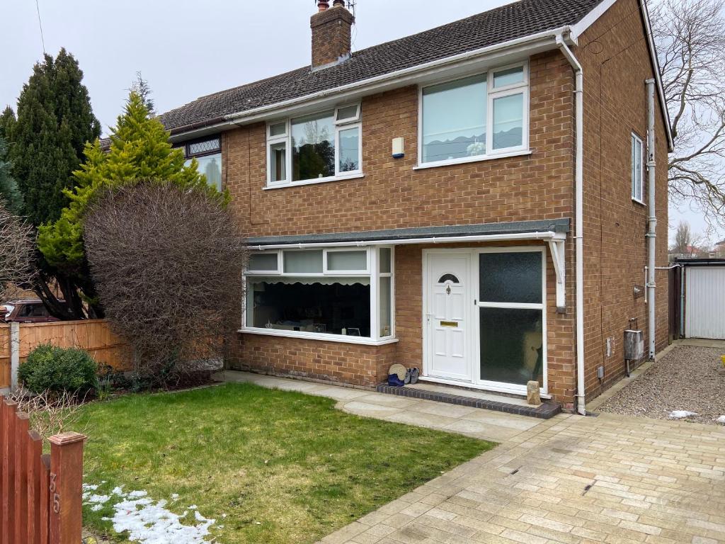 伯肯黑德Cumberland Avenue prenton Wirral 3bed detached house with a lovely view looking out on to a field from the rear close to all amenities的砖屋,有白色门