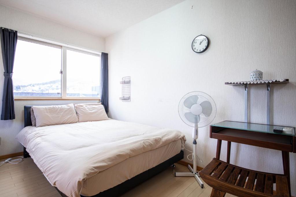 小樽Sumiyoshi House Room B的一间卧室配有一张床、一张桌子和闹钟
