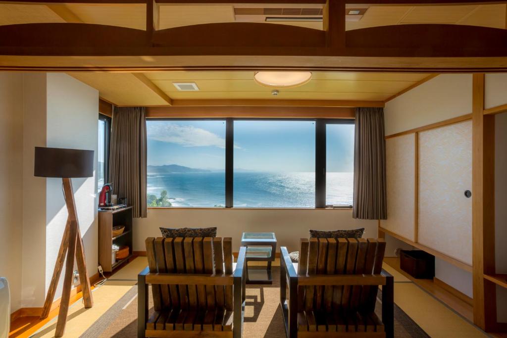 京丹后市尤凯特酒店的客厅配有桌椅和大窗户
