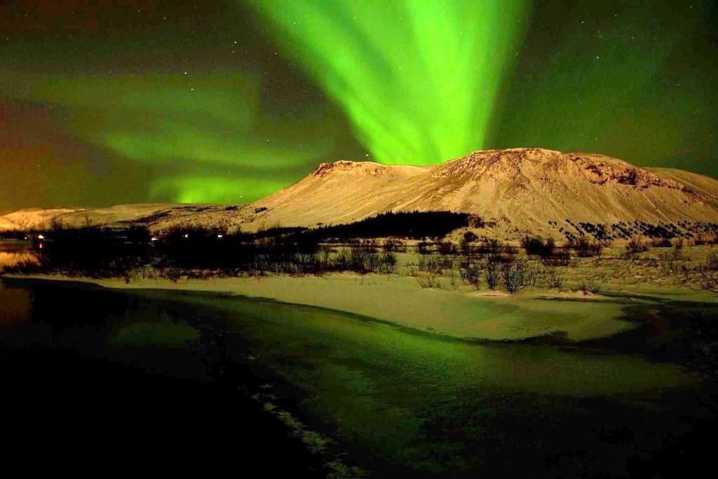 莫斯费德斯拜尔Paradise near Reykjavik w. Sauna - Northern Lights的山上方的极光和水体