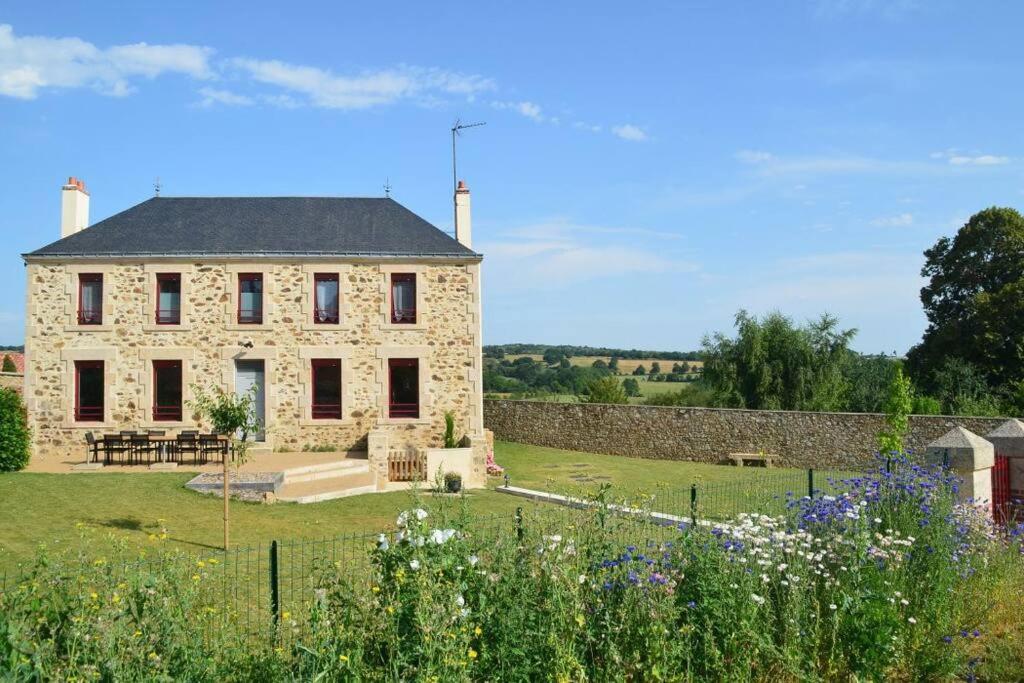 SevremontGîte La Dortière s'Amuse, magnifique maison de maître 12min du Puy du Fo的一座大型石头房子,前面设有一个花园