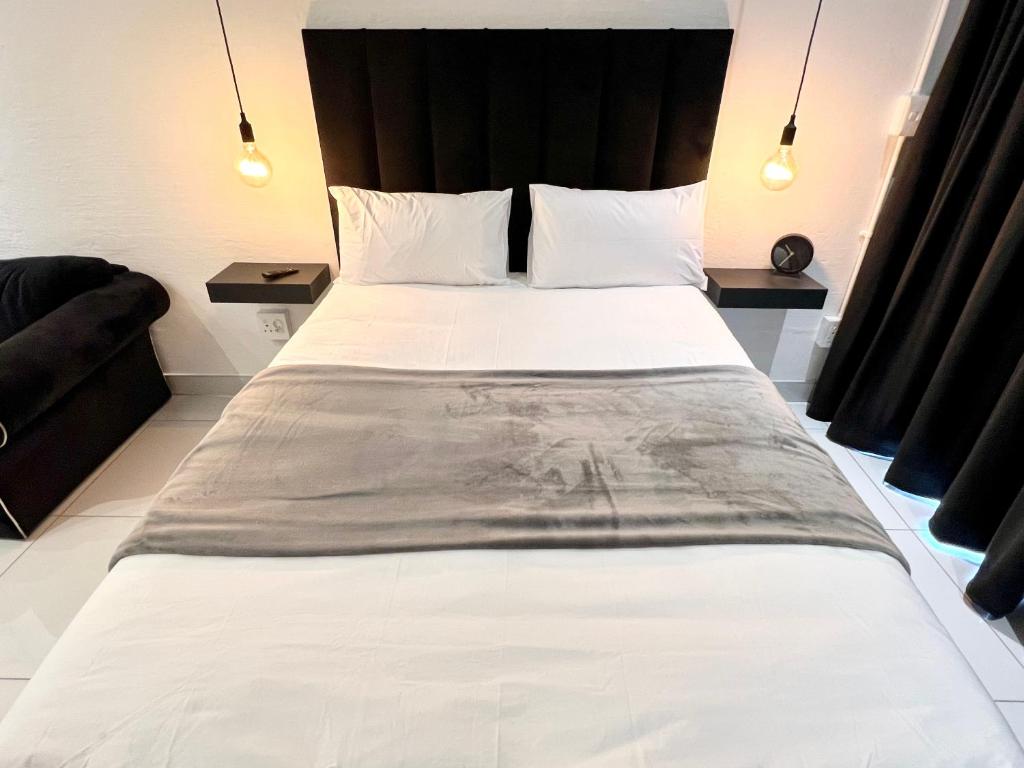 约翰内斯堡Industrial CHIC Apartment 113的一间卧室配有一张白色大床和黑色床头板