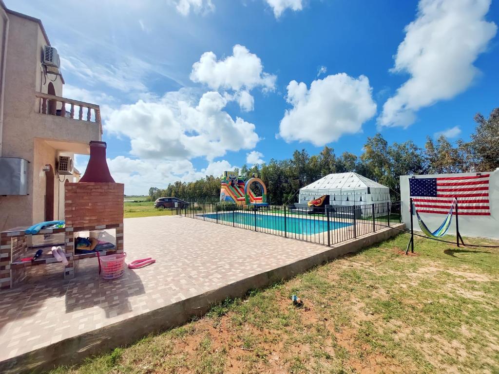 American Farm Villa Grand Casablanca/El Jadida的一个带游泳池和美洲旗的游乐场