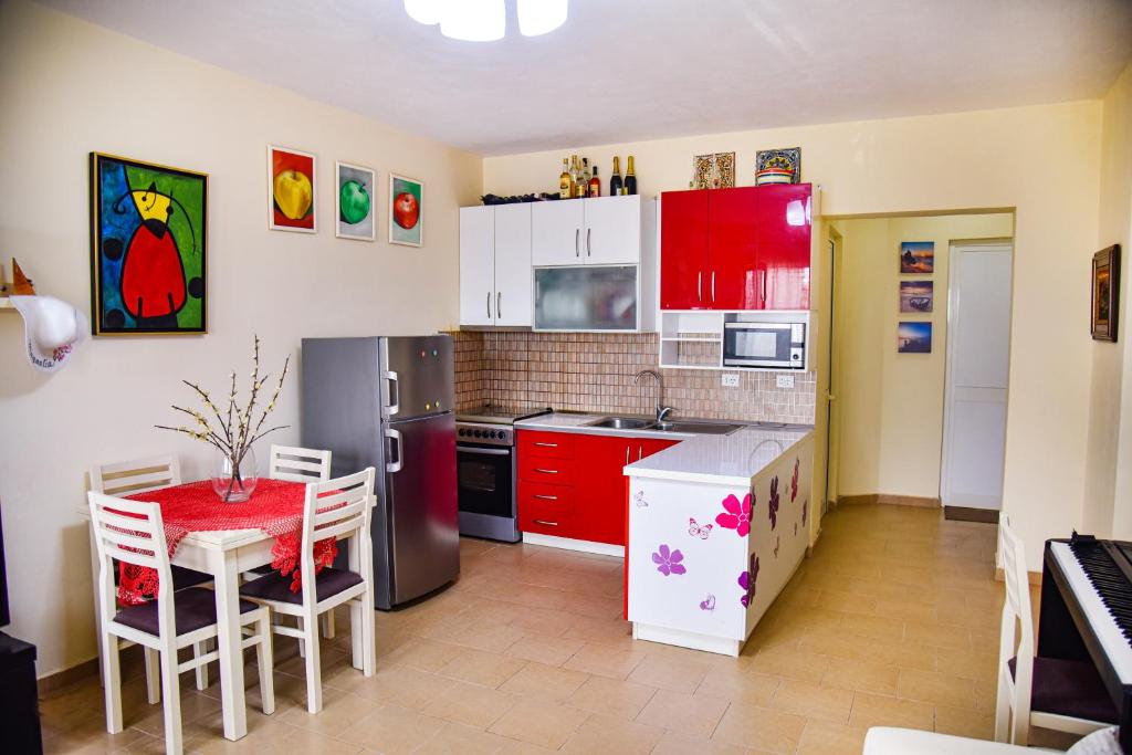 维利波吉White Sea View Apartment Velipoje的厨房配有红色橱柜和红色的桌椅