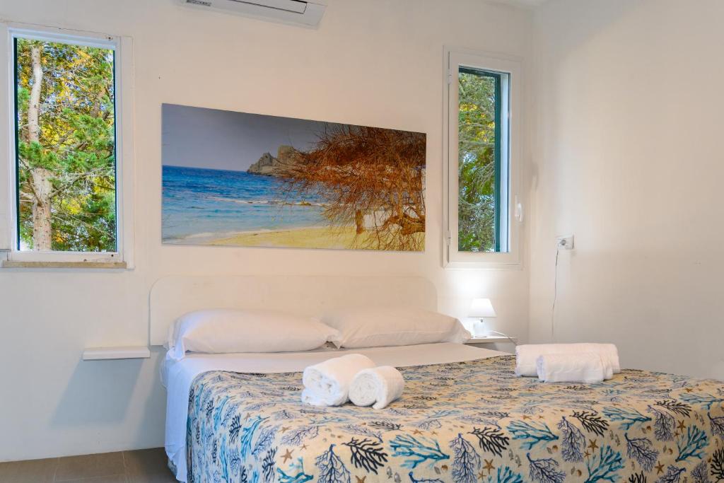 圣凯撒利亚温泉Camping La Scogliera的一间卧室设有两张床和两个窗户。