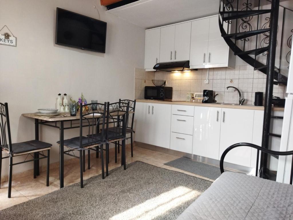 AlepouChristina's House的厨房配有白色橱柜和桌椅