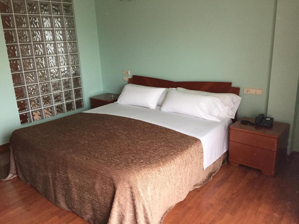 CatoiraMotel Abalo的一间卧室设有一张大床,铺有木地板