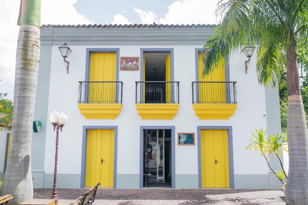 蒂拉登特斯Pousada Relicário的白色的建筑,有黄色的门和棕榈树
