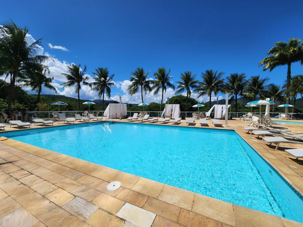 尼泰罗伊Apart Hotel Alecrim Praia de Camboinhas com Marina pe na areia的一个带躺椅的游泳池,棕榈树
