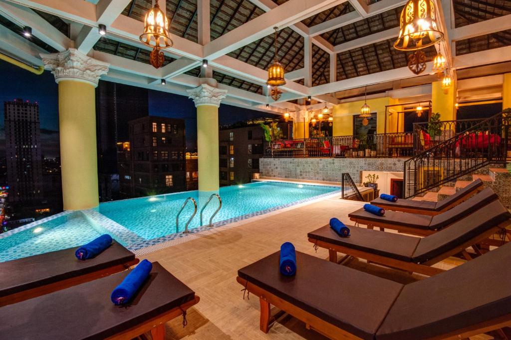 金边高棉苏林精品旅馆的一座大型游泳池,位于酒店,设有沙发和游泳池