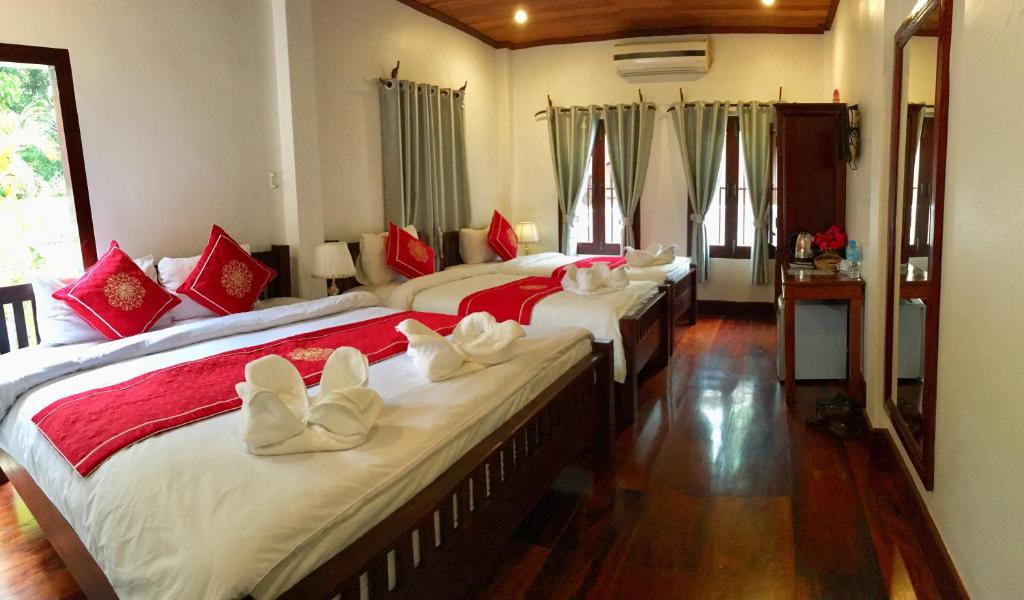 琅勃拉邦Luang Prabang Pangkham Lodge的一间卧室配有两张带红白色枕头的床