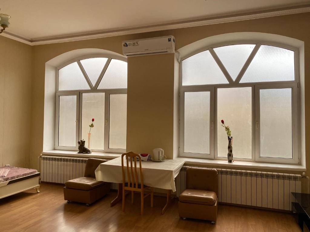 舍基Beaming_House的一间设有两扇窗户和一张桌子及椅子的用餐室