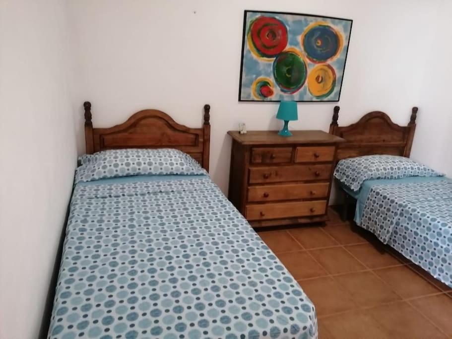 Abadeshabitación en un bajo 2 camas individual casa compartida的一间卧室设有两张床,墙上挂着一幅画