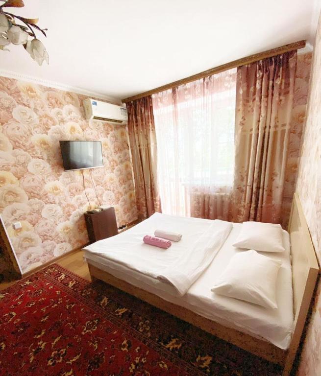 (( Turksib ))Квартира напротив Аэропорта的卧室配有白色的床和墙上的电视。