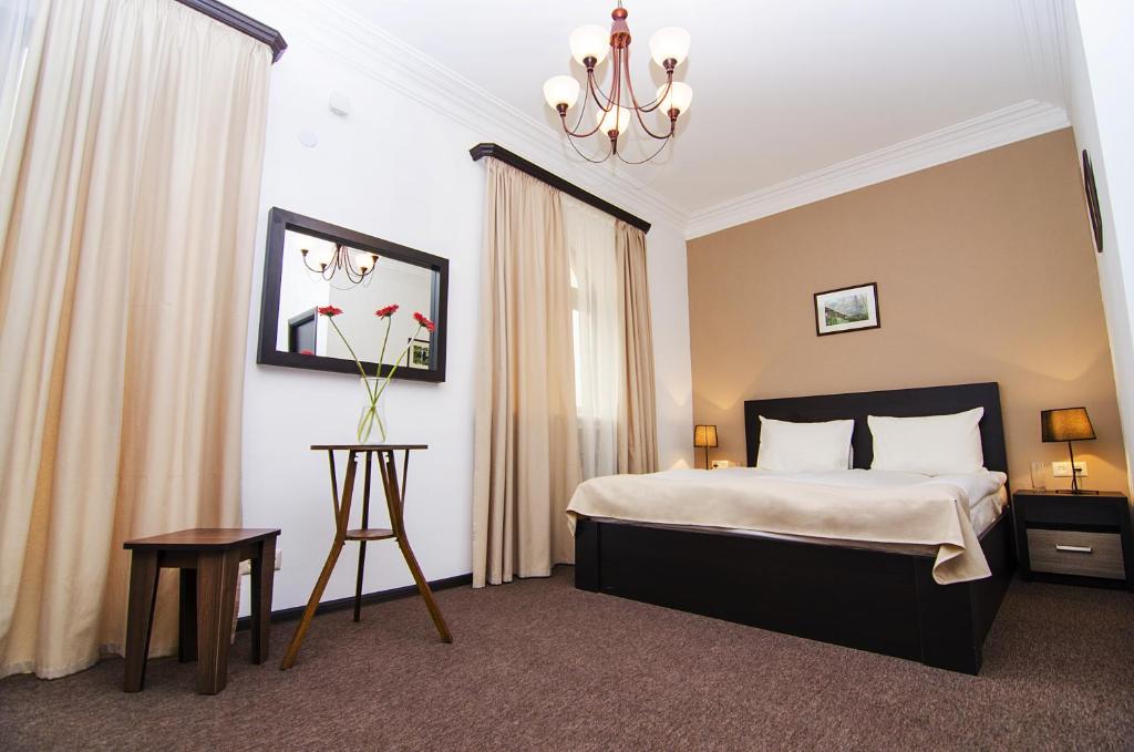 埃里温城市中心酒店的酒店客房,配有一张床和吊灯