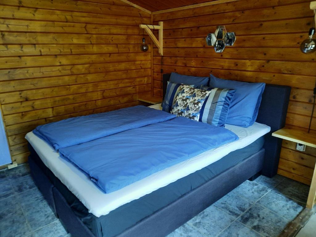 WapenveldB&B Paardenhof的配有木质墙壁的客房内一张带蓝色床单的床