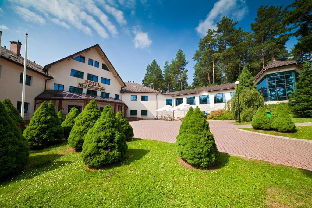 恰尔纳Hotel Perła Bieszczadów Geovita的建筑物前的一排树木