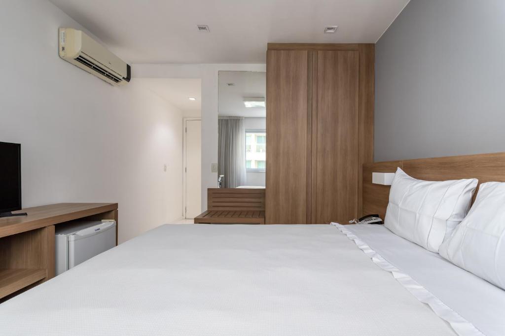 里约热内卢Flat Barra Da Tijuca的卧室配有一张白色大床和电视。
