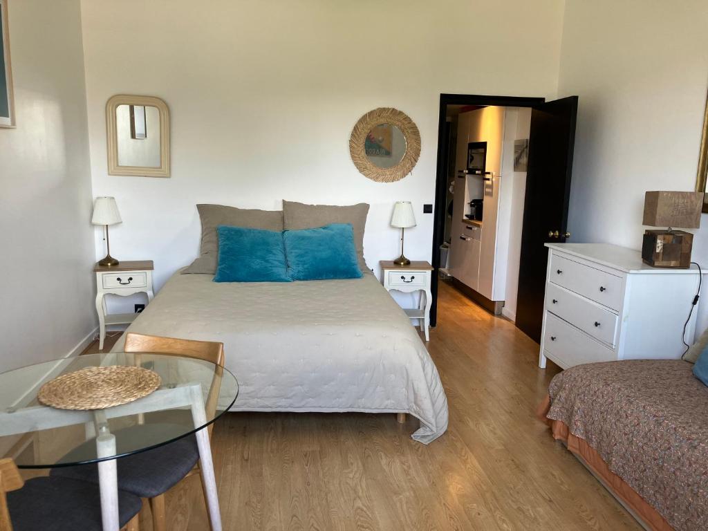比亚里茨Studio phare de Biarritz Résidence Régina Golf的一间卧室配有一张带蓝色枕头的床和一张桌子