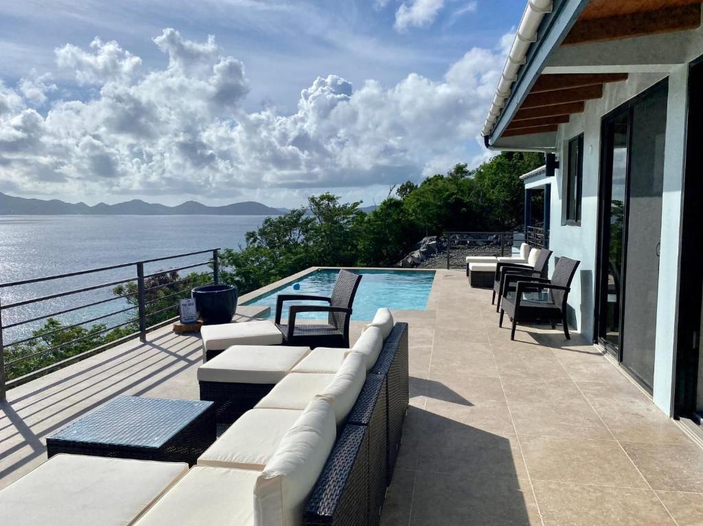 Jost Van DykeJost Van Dyke, BVI 3 Bedroom Villa with Caribbean Views & Pool的一个带椅子的庭院、一个游泳池和大海
