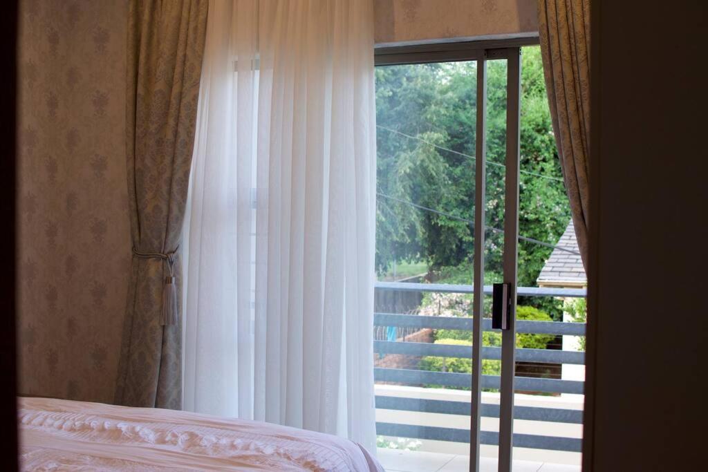 比勒陀利亚Park Central Apartment的卧室设有窗户,可眺望阳台