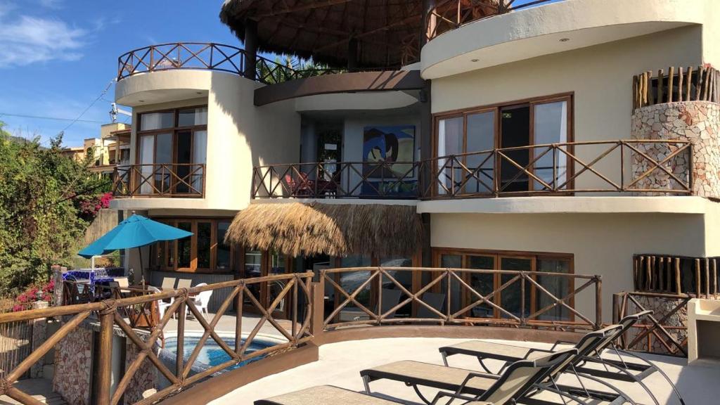 Higuera BlancaLitibu Suites Beach House的带阳台的房屋,配有椅子和游泳池