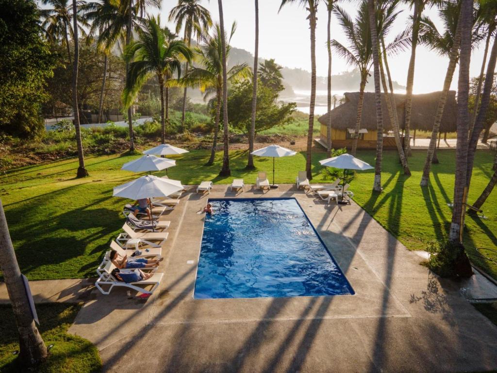 圣法兰西斯克Hotel Ysuri San Pancho的享有带椅子和遮阳伞的游泳池的上方景致