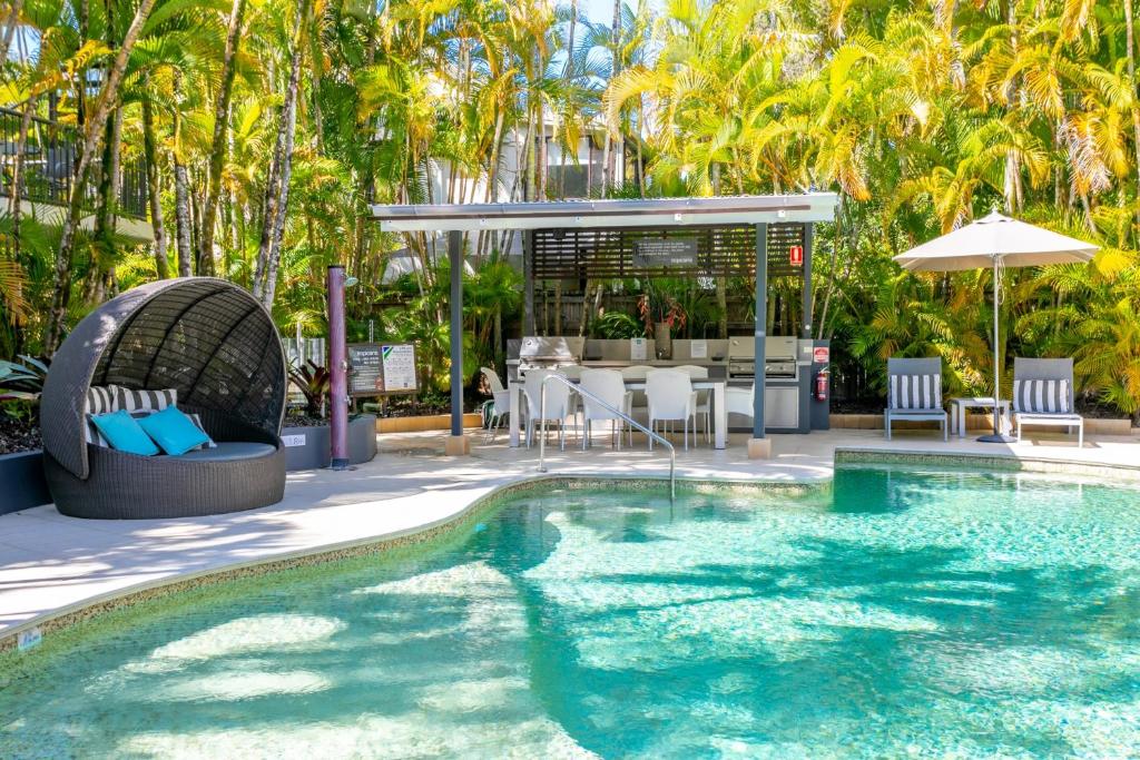 努萨维尔努沙康纳酒店的度假村的游泳池配有桌椅