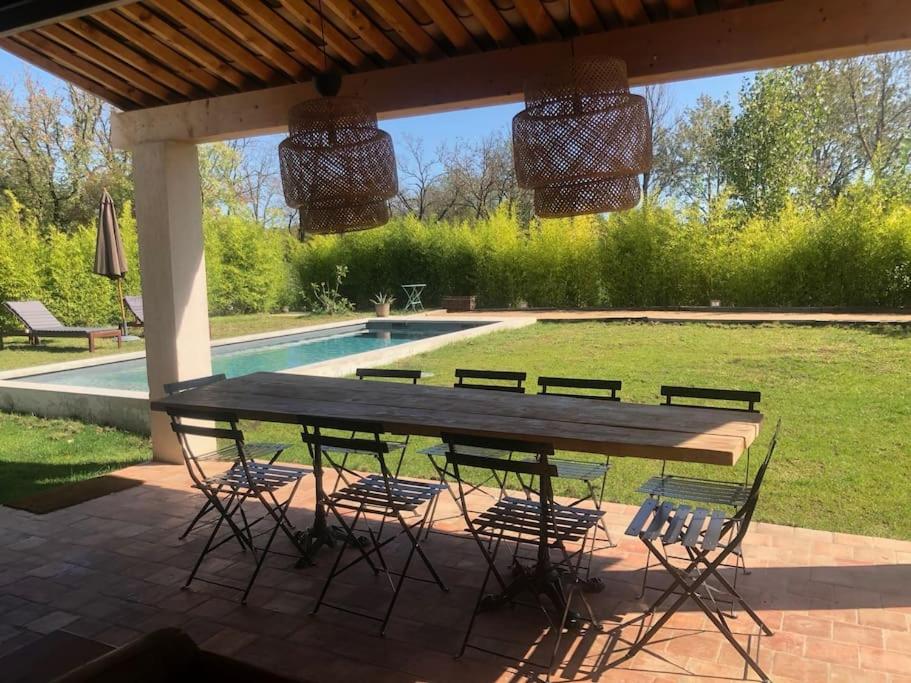 格里莫Villa neuve et moderne avec piscine à Grimaud的一个带游泳池的凉亭下的野餐桌椅