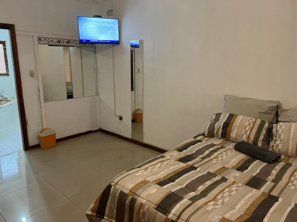 恩潘盖尼Empangeni guest house的卧室配有一张床,墙上配有电视。
