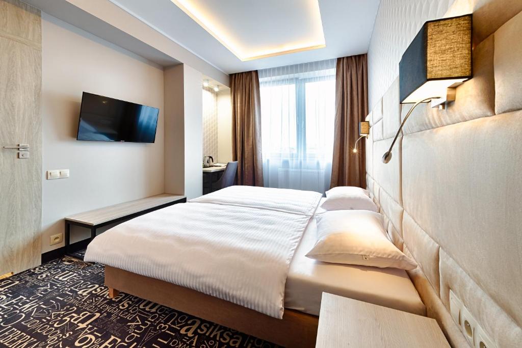 罗兹Citi Hotel's Łódź的配有一张床和一台平面电视的酒店客房