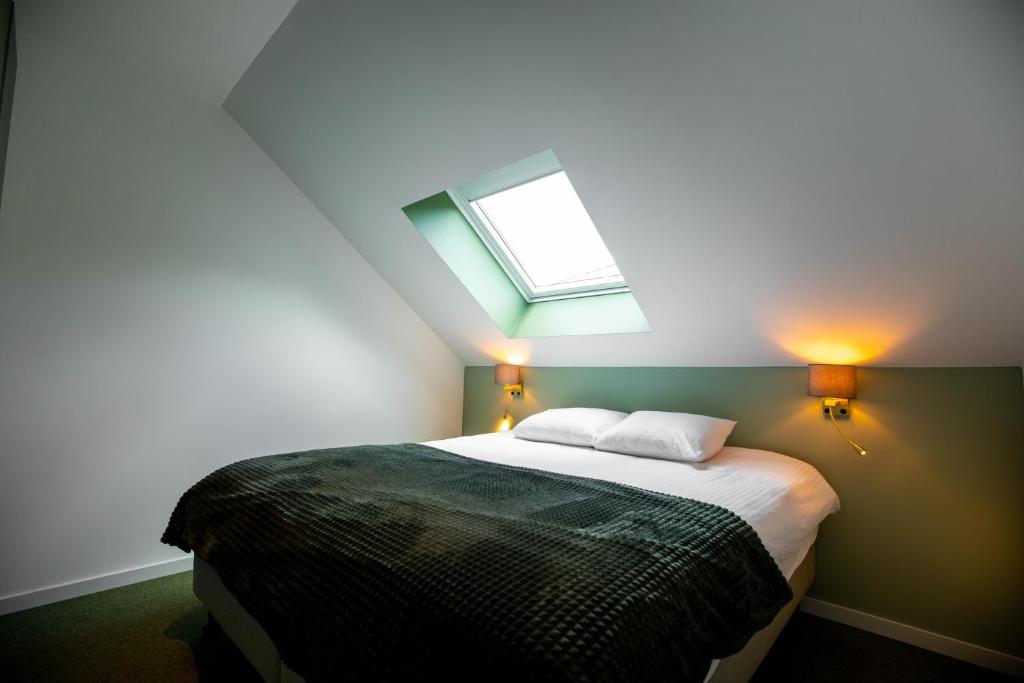 亨克City Housing Genk的一间卧室配有一张带天窗的床
