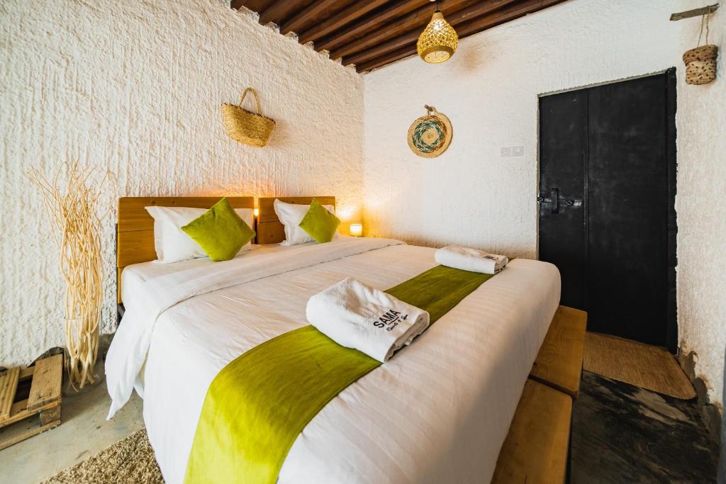 尼兹瓦SAMA Al Khutaim-Heritage Home的一间卧室配有一张带绿色和白色床单的大床