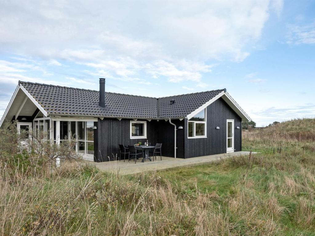 希茨海尔斯Holiday Home Frejdis - 1-1km from the sea in NW Jutland by Interhome的田野边的黑色房子