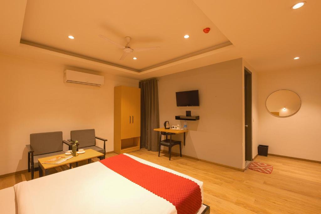 新德里The Grand Tashree at Delhi Airport的一间卧室配有一张床、一张桌子和一台电视。