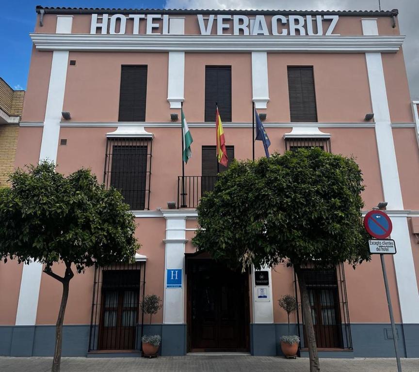 乌特雷拉Hotel Veracruz的前面有两面旗帜的粉红色建筑