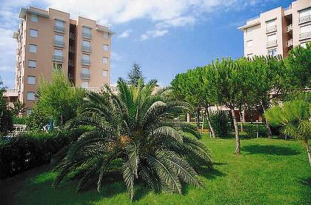 马瑟利Trilo Conero, in residence con piscina ed aria condizionata vicino al mare的一座建筑前的公园里的棕榈树