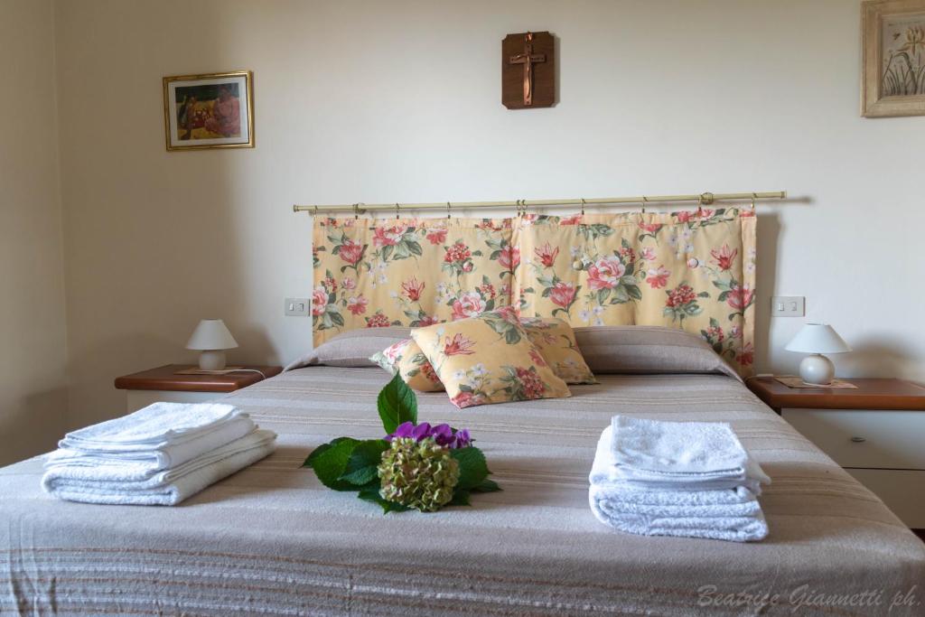 LuniAppartamento per Vacanze Domus Lunae的一间卧室配有带毛巾和鲜花的床