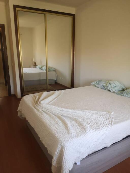 埃斯托伊Maravilhoso apartamento T2 Estoi的卧室配有一张带镜子的白色床
