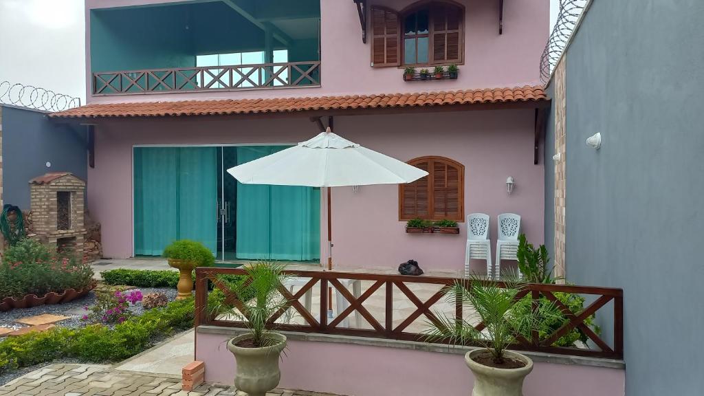 维索萨-杜塞阿拉Casa de Serra Vila Viçosa的粉红色的房子,配有雨伞和阳台