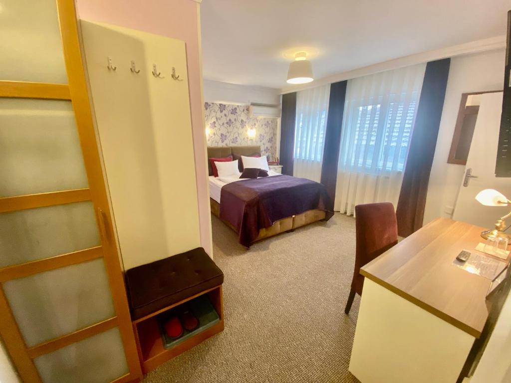 萨拉热窝Halvat Guesthouse的酒店客房配有一张床铺、一张桌子和一张书桌。