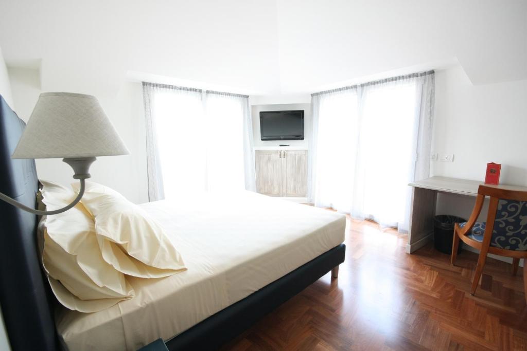 科莫皮林纽斯酒店的一间卧室配有一张带灯的床和两个窗户