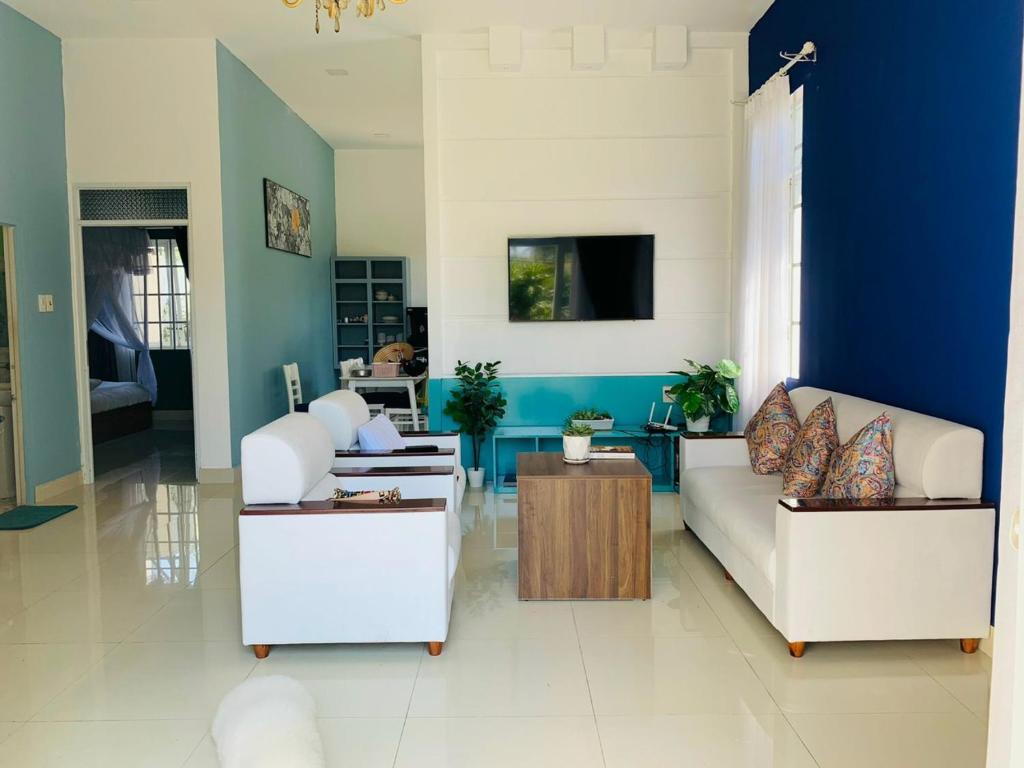 保禄Mon House的客厅配有2张白色沙发和1面蓝色的墙壁